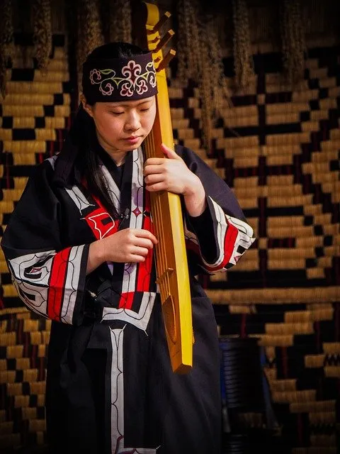 Kobieta Ainu gra muzykę Artykuł o ajnuskiej wiosce Shiraoi na Hokkaido - jak żyli Ainu 500 lat temu - spacer przez ajnuską wioskę.