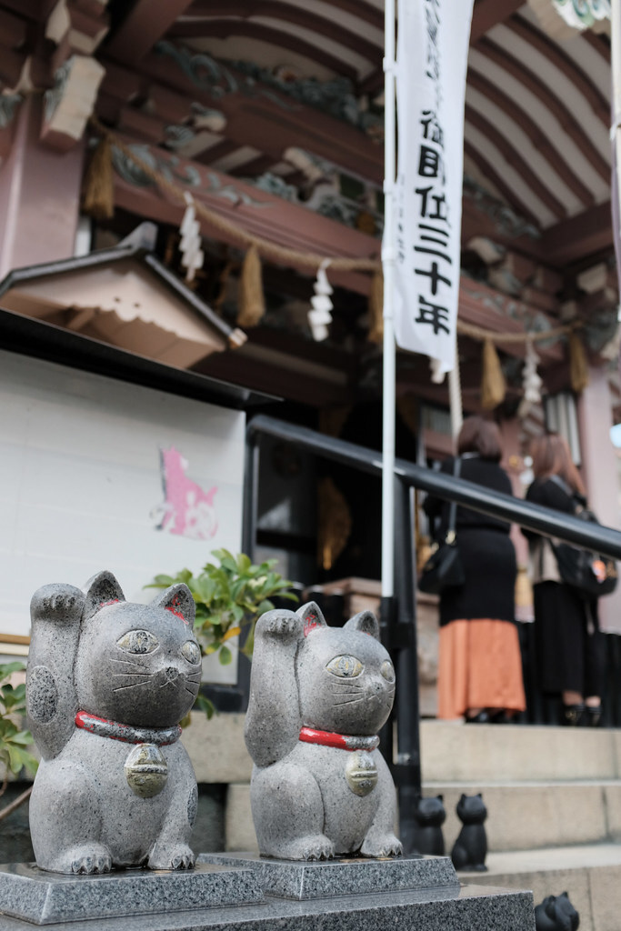 Maneki-neko przy wejściu do świątyni Esej o Maneki-Neko - czym jest, jakie są legendy z nim związane i jakie znaczenie od czasów Edo po współczesną Japonię.