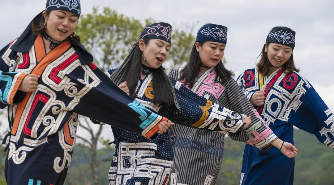 Ainu women performing a dance in their colorful clothes, traditions of northern Japan - Hokkaido and Sakhalin as well. Essay about Polish researchers' role in reasearch of the Ainu people - Ainu living on Hokkaido and Sakhalin. Role of Bronislaw Pilsudski in early linguistic and cultural research of Ainu people of Northern Japan.