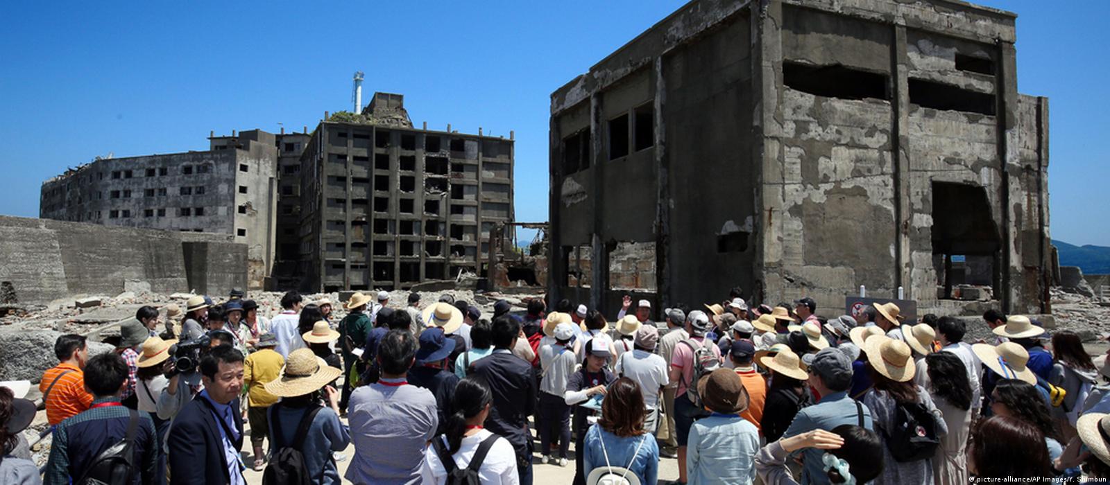 Turyści w XXI wieku na ghost Town Hashima (Gunkanjima, Japonia) Artykuł o japońskiej wyspie ghost town: Hishima (Gunkanjima). Japońskie wymarłe miasta. Hashima.
