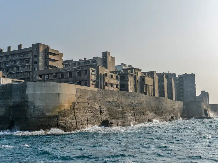 Japońska wyspa ghost town Gunkanjima (Hashima) ma mury jak w Attack on Titan. Artykuł o japońskiej wyspie ghost town: Hishima (Gunkanjima). Japońskie wymarłe miasta. Hashima.